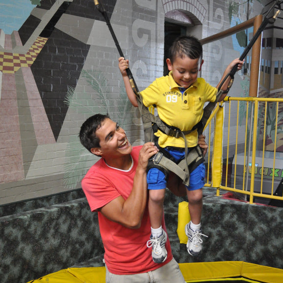 Trampoline Thing at ZDT's Amusement Park - Child getting ready to bounce on a bungee trampoline assistant by an attendant.