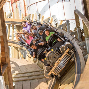Switchback Roller Coaster - Riders being launched through a building on a wooden shuttle roller coaster.